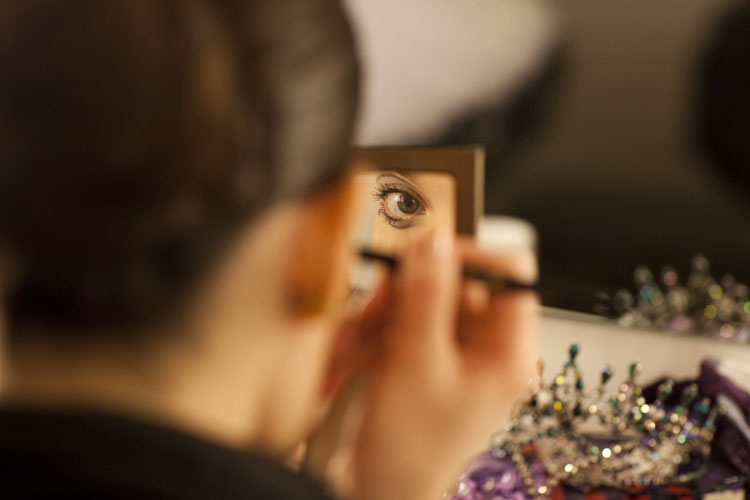 A ballerina applying her make-up in the mirror, backstage at The Colosseum in Watford