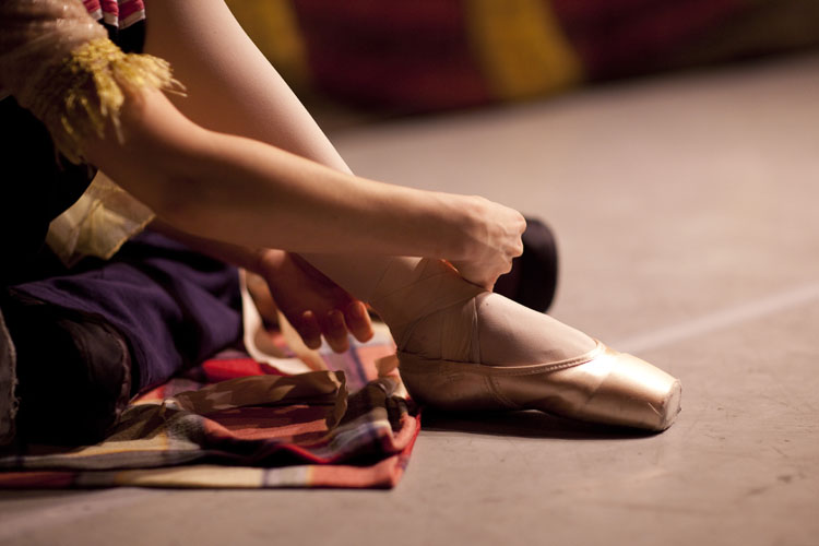 A ballerina from the Russian State Ballet of Siberia doing up her shoes. Copyright Helen Maybanks 2011