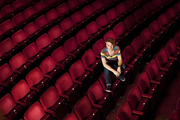 Colour photograph of Steven Webb seated in an empty theatre.