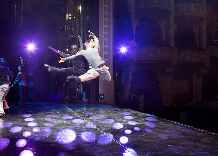Two dancers leap across the stage during Burn the Floor rehearsals
