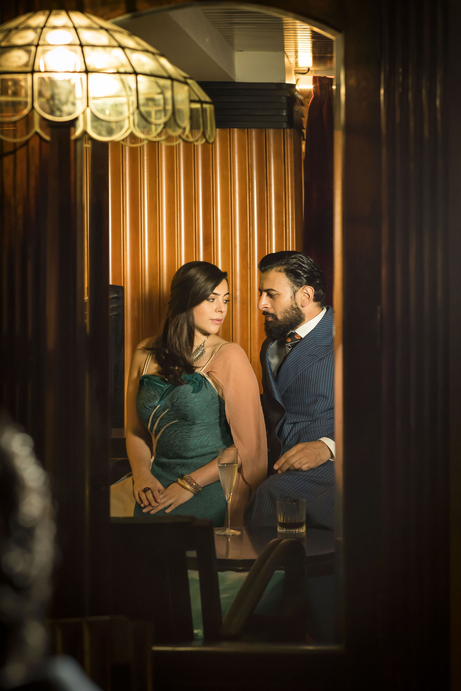 A reflection of Sophie Khan Levy as Ursula and Vikash Bhai as Cyrus Irani in the Art Deco surroundings of Dishoom in Kensington